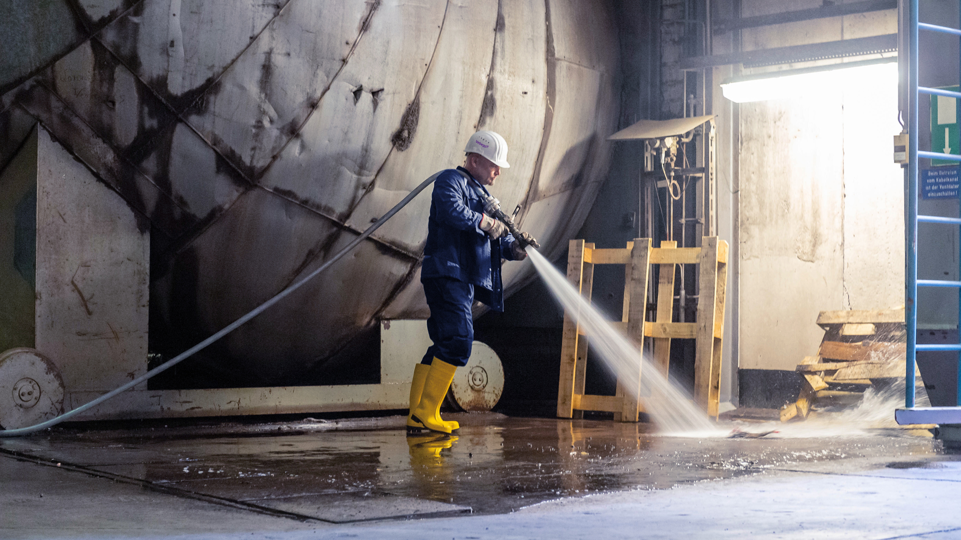 Mitarbeiter reinigt mit Hochdruckreiniger Hallenboden 